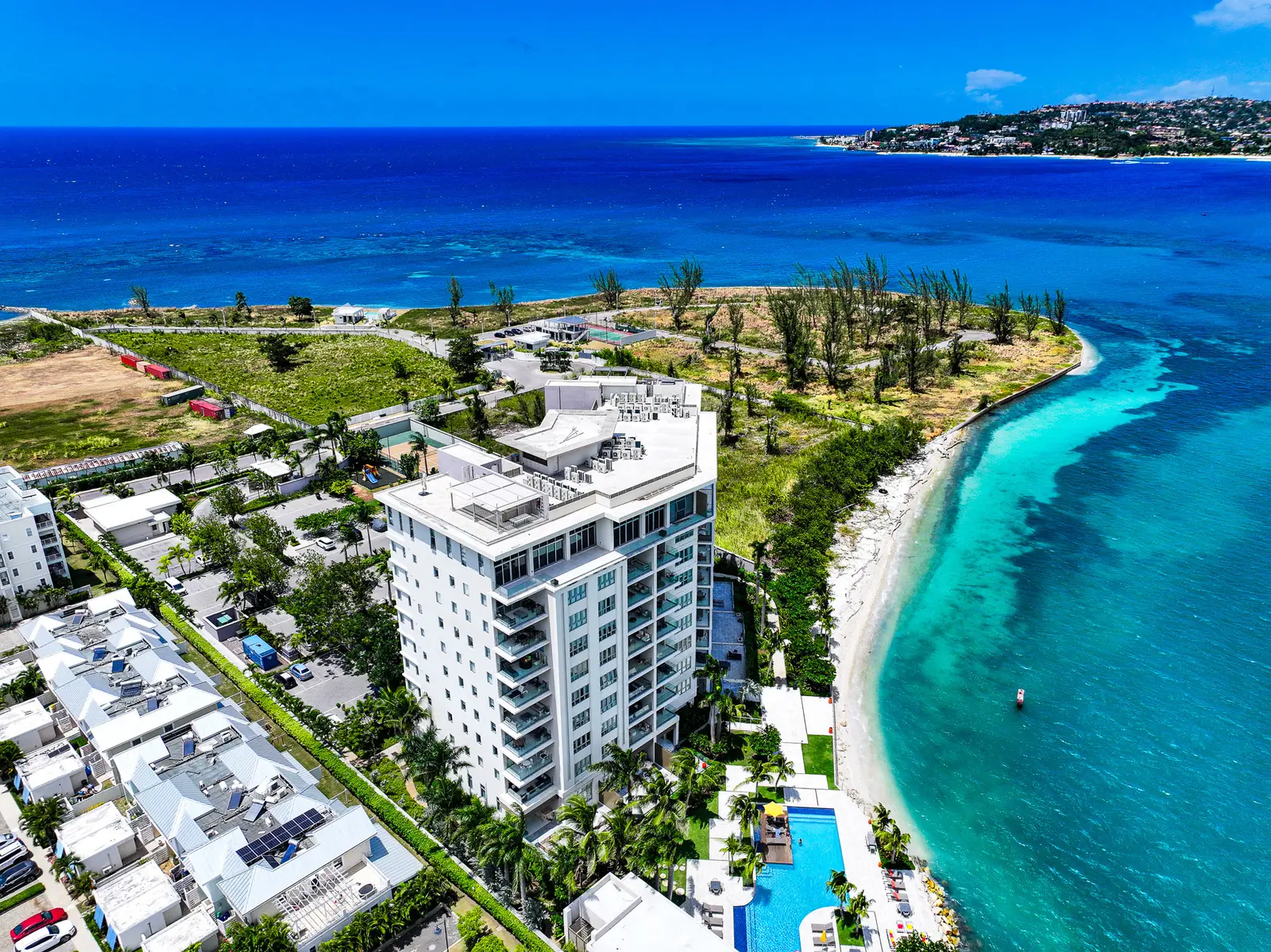 Aerial view of Soleil Residences on the Freeport waterfront in Montego Bay, Jamaica, beside a white-sand beach and turquoise sea