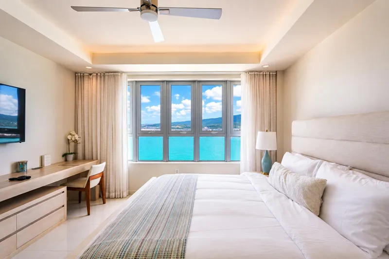 Bright bedroom with ocean-view windows at Soleil Residences, Freeport, Montego Bay