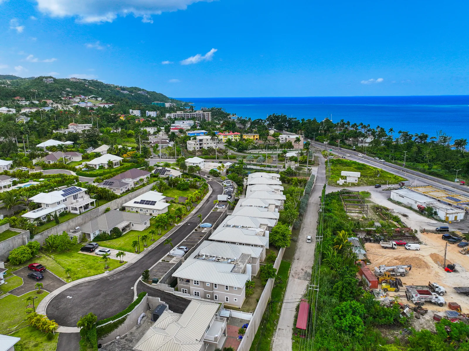 Aerial view of the TARA Apartments community with townhouses stepping down the hillside toward the sea