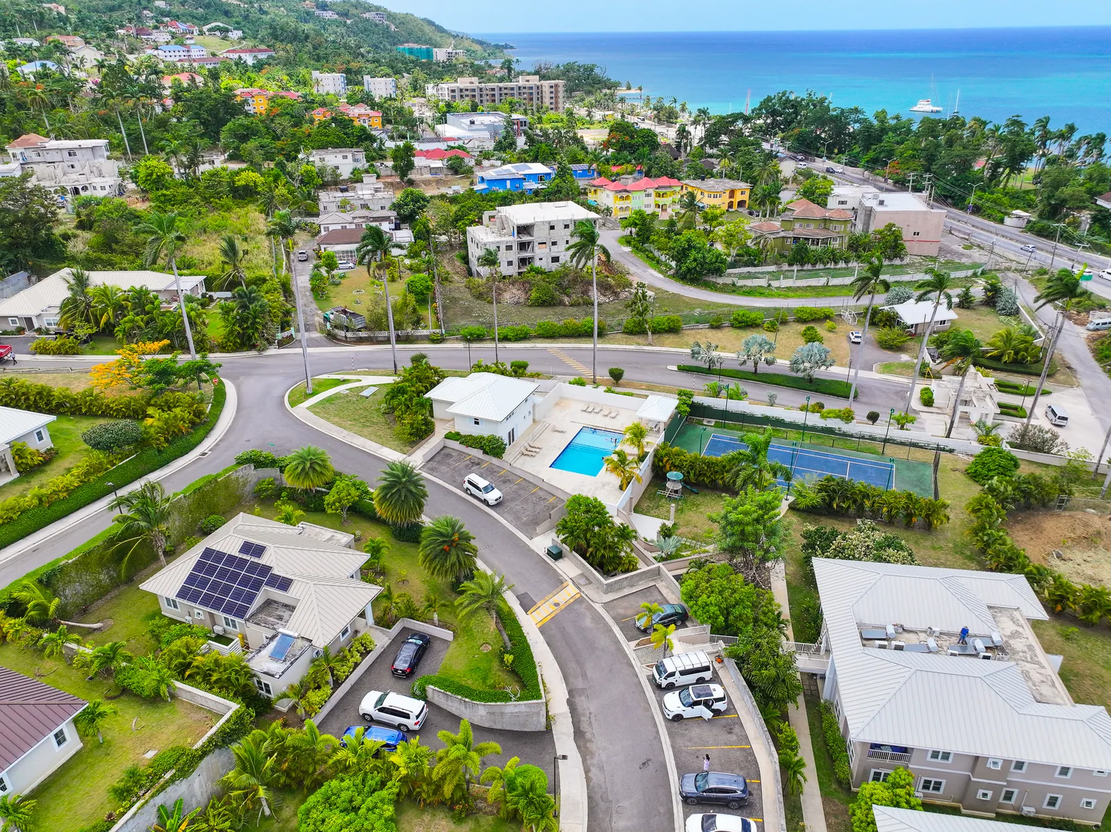 Aerial view of the TARA Apartments community, with pool, tennis court and the sea beyond